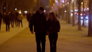 Romantik bir çift gece Paris 'te el ele yürür. Fransa' da ağaçlar ve şehir ışıkları arka planda bulanıklaşır. Bir yakınlık ve aşk hissi yaratır..
