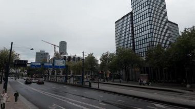 ROTTERDAM, NETHERLANDS - 13 Eylül 2025 - Rotterdam 'da şehir caddesi modern ofis binaları, arabalar, ağaçlar ve yayalar