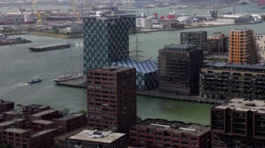 ROTTERDAM, NETHERLANDS - 13 Eylül 2025 - Rotterdam rıhtımı boyunca yoğun limandaki gemilerle çağdaş binalar yükseliyor