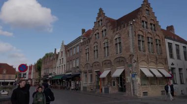 BRUGES, BELGIUM - 15 Eylül 2025 - İnsanlar Bruges 'de geleneksel tuğla cepheleriyle dolu bir sokakta yürüyor