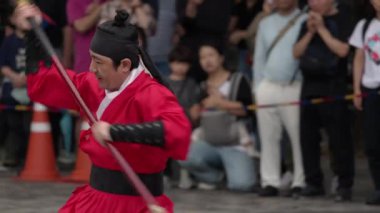 SEOUL, Güney Kore - 11 Ekim 2025 - Kırmızı Hanbok 'taki erkek sanatçı geleneksel bir kılıç dansını Seul' deki kalabalığa gösteriyor