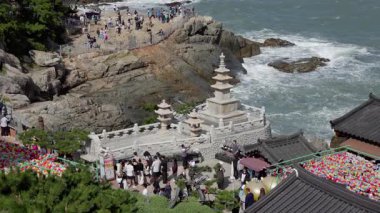 BUSAN, Güney Kore - 10 Ekim 2025 - Haedong Yonggungsa tapınağı pagoda ve kayalık kıyılarda okyanus dalgaları ve ziyaretçi turistlerle birlikte mimari