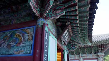 BUSAN, Güney Kore - 10 EKİM 2025 Busan, Güney Kore 'deki bir Budist tapınağında boyalı saçaklar ve canlı bir ejderha resmi