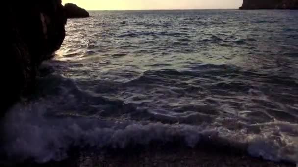 Water van de Oceaan op een rotsachtige kust in de avond — Stockvideo