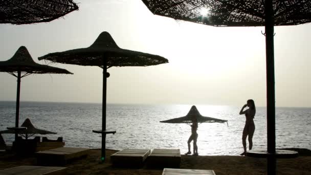 Hermosa madre e hija se encuentran con el amanecer en el mar — Vídeos de Stock