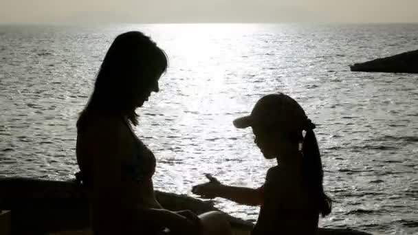 Mãe e filha mostram gestos ao nascer do sol perto do mar — Vídeo de Stock
