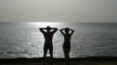 Çift gündoğumu deniz kenarında karşılar