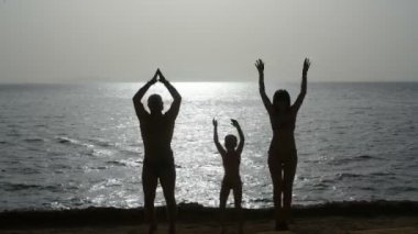 Genç aile gündoğumu deniz kenarında dans