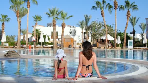 Madre e figlia a riposo, chiacchierando in piscina — Video Stock