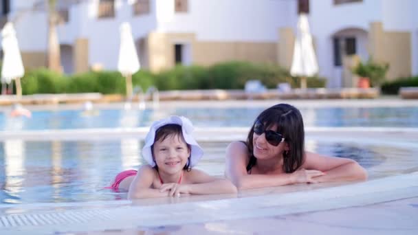 Madre e hija descansando, charlando en la piscina — Vídeo de stock