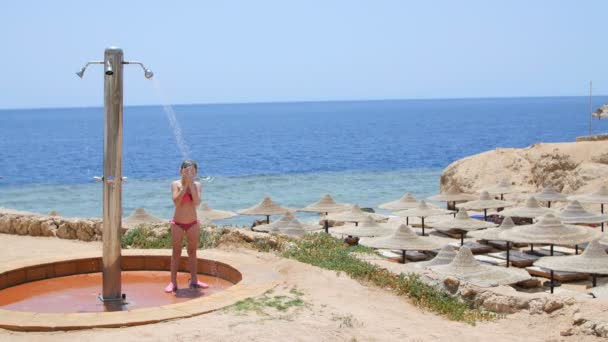En vacker liten flicka att städa duschen på bakgrund av havet — Stockvideo