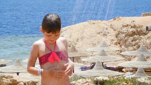 Красивая маленькая девочка, чтобы очистить душ на фоне моря — стоковое видео