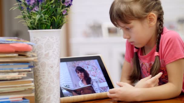 母亲读一本书通过他女儿的平板电脑 — 图库视频影像