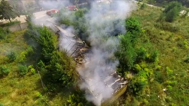 Huis staat in brand - Brandweerlieden blussen van een brand met water. Luchtfoto — Stockvideo