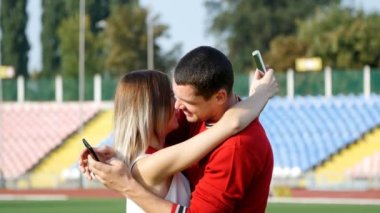 genç bir adam ve güzel kız - futbol sahasına, cep telefonunuzda bir iletiyi okumayı