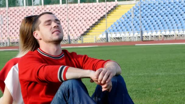 Genç bir adam ve güzel bir kız Stadyumu'nda - tarlanın ortasında oturuyor — Stok video