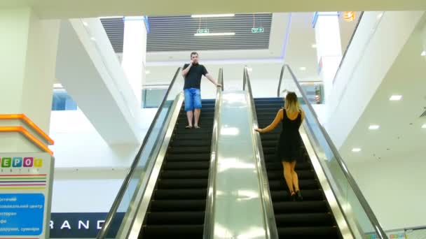 Beautiful girl and the young man saw each other on the escalator — Stock Video