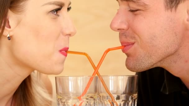 Uma menina bonita e um jovem bebendo suco através de uma palha — Vídeo de Stock