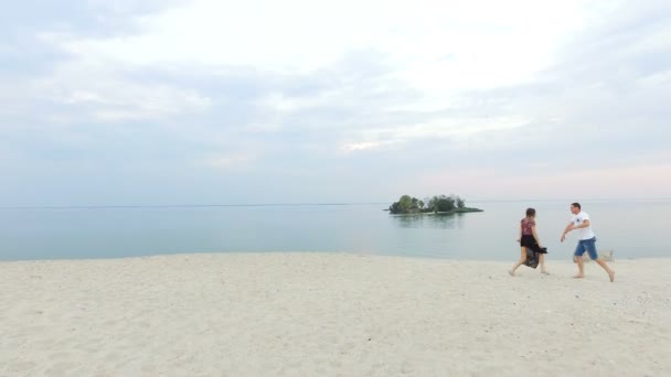 Vacker flicka och hennes pojkvän som leker på stranden - kille doganyaet flickan och kysser henne — Stockvideo