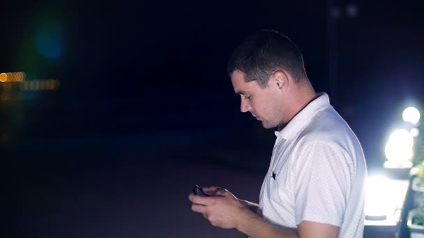 Man reading a message on your mobile phone - near the lanterns at night — Stock Video