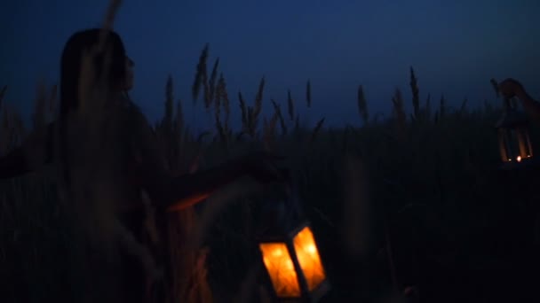 Gyönyörű lány sétál a mező - gazdaság gyertya lámpák kezében — Stock videók