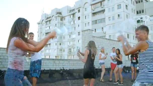 Meninos e meninas derramando água engarrafada sobre as pessoas - diversão dos jovens — Vídeo de Stock
