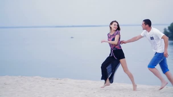 Mädchen und der Typ, der auf dem Sand am Meer läuft - lieben lustige Spiele — Stockvideo