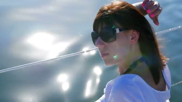 Portré egy lány, aki egy jachton - pihen a nap fénye a vízben — Stock videók