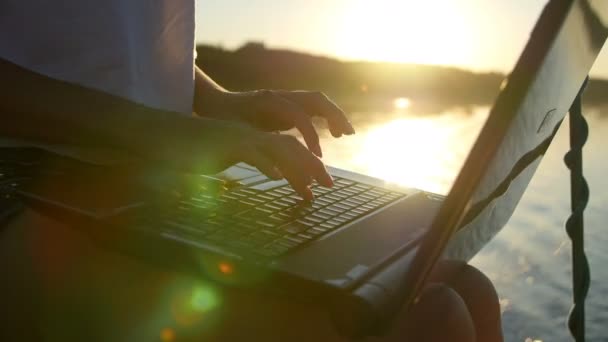 Jacht meisje werkt op een laptop - schittering van de zon in het water — Stockvideo
