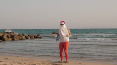 Noel Baba yaz tatili. Noel Baba eğleniyor. Güneş gözlüklü ve paletli komik Noel Baba, sahilde dans ediyor ve dinleniyor. Noel Baba şnorkelle dalacak