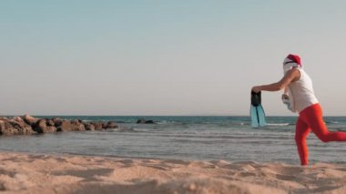 Noel Baba yaz tatili. Noel Baba eğleniyor. Güneş gözlüklü, yüzgeçli ve şnorkelli komik Noel Baba deniz sahilinde koşar. Yüzmek için acele ediyor, şnorkel..