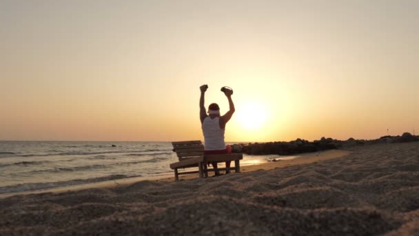 Der Weihnachtsmann tanzt. Lustiger Weihnachtsmann, der mit einem drahtlosen Bluetooth-Lautsprecher in der Hand vor Sonnenuntergang oder Sonnenaufgang tanzt. Rückseite. Entspannen Sie sich am Strand am Meer — Stockvideo