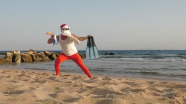 Noel Baba yaz tatili. Noel Baba, eğleniyor. Noel Baba yoga yapıyor. Komik Noel Baba, güneş gözlüklü, yüzgeçli ve şnorkelli, deniz kenarında. Noel Baba şnorkelle dalacak