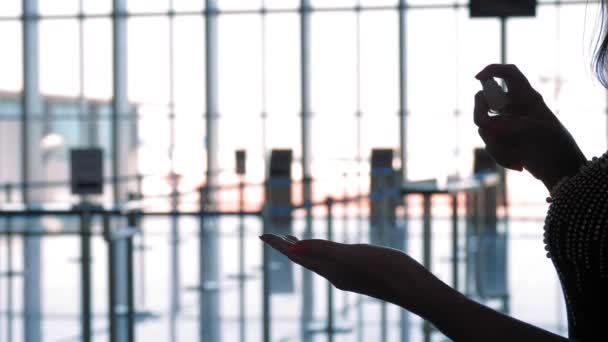 Ruční antiseptikum na letišti. detailní záběr. černé obrysy ženských rukou na pozadí prázdného letiště, během pandemie koronaviru nebo uzamčení. — Stock video