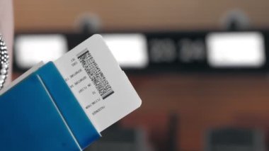 Yakın plan. Havaalanındaki boş kayıt gişelerine karşı elinde uçak bileti ve pasaport tutan bir kadın. Uçakla seyahat etmek..