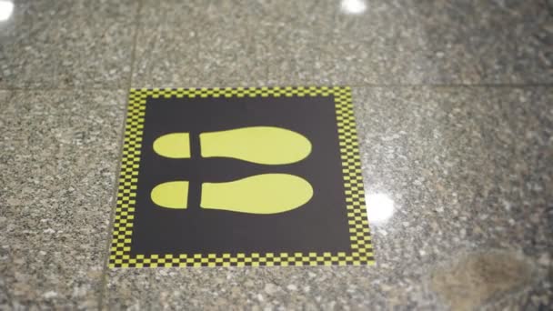Знаки слідів. соціальне дистанціювання. жовті позначки на підлозі для підтримки соціальної відстані між людьми під час епідемії коронавірусу. крупним планом. в аеропорту. Нові обмежувальні заходи щодо ковадла-19 — стокове відео