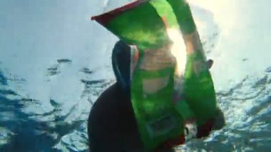 Denizde ya da okyanusta çöp toplama. Adam, şnorkel maskesi takıyor, yüzüyor ve suya atılmış çöpleri topluyor. Yakın plan. Deniz, okyanus kirliliği. çevre koruması,