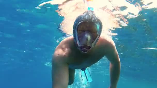 Muž šnorchluje. plavec, v šnorchlovací masce, šnorchluje v moři a bere selfie s kamerou pod vodou. sluneční svit osvětluje hladinu vody. — Stock video