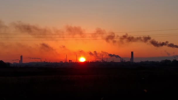 Jasny pomarańczowy zachód słońca w przemysłowym mieście. ciemne kontury, sylwetki kominów fabrycznych na czerwonym tle zachodzącego słońca. — Wideo stockowe