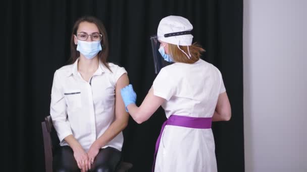 Coronavirus aşısı. Hemşire ya da doktor, tıbbi maske ve koruyucu eldivenlerle aşı şırıngası ile aşı yapar. Aşı prosedürü. Koronavirüse karşı aşı. — Stok video