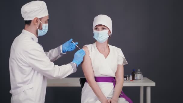 Vacunación contra el Coronavirus del personal médico, médicos. enfermera, en máscara protectora y guantes médicos, hace la vacunación con jeringa de vacuna al médico. vacunación con covid-19. — Vídeos de Stock