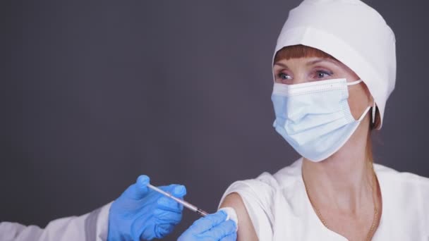 Coronavirus vaccination of medical personnel, doctors. nurse, in protective gloves, injects the vaccine into patients shoulder. covid-19 vaccination. — Stock Video