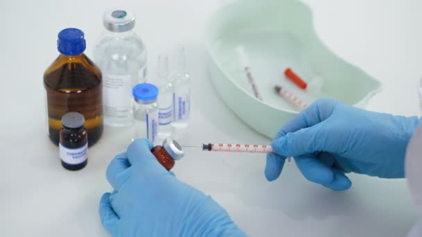 Coronavirus vaccination. close-up, hands of nurse, in medical gloves, draws liquid vaccine from small glass bottle into syringe for patient to be injected, vaccinated. global, mass vaccination for — Vídeo de Stock