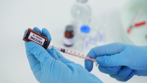 Coronavirus vaccination. close-up, hands of nurse, in medical gloves, draws liquid vaccine from small glass bottle into syringe for patient to be injected, vaccinated. global, mass vaccination for — Wideo stockowe