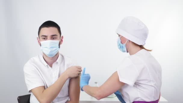 Coronavirus vaccination. nurse or doctor, in protective mask and medical gloves, injects vaccine into patients shoulder in clinic. new vaccine for prevention, immunization and treatment of — Stockvideo