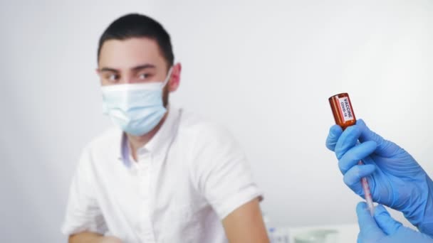 Coronavirus vaccination. nurse or doctor, in protective mask and medical gloves, draws liquid vaccine from small glass bottle into syringe for patient to be injected, vaccinated. global, mass — Stok Video