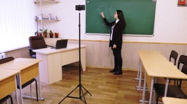 Çevrimiçi eğitim, e-öğrenme. Bayan öğretmen online ders veriyor, uzaktan, akıllı telefon webcam 'i kullanarak. Okul sınıfından öğrenciler için canlı yayın. uzaktan eğitim, koronavirüs sırasında öğrenme