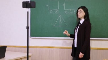 Çevrimiçi eğitim, e-öğrenme. Bayan öğretmen online ders veriyor, uzaktan, akıllı telefon webcam 'i kullanarak. Okul sınıfından öğrenciler için canlı yayın. uzaktan eğitim, koronavirüs sırasında öğrenme
