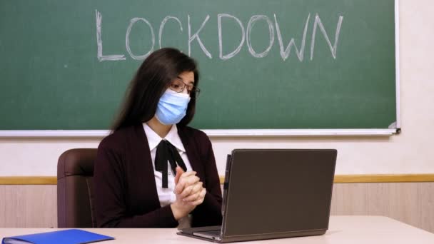 Fjernundervisning, afspærring på skoler. Online skolegang, e-læring. Kvindelig lærer, i beskyttende maske, holder online lektion for studerende, eksternt, ved hjælp af bærbar computer, fra skole klasse. Online på nettet – Stock-video