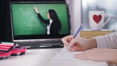 Uzaktan öğrenme, online eğitim. Laptop ekranına yakın çekim. Liseli kız çevrimiçi video dersi izliyor ve not defterine not alıyor. Evde online ders çalışıyorum..